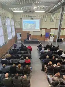 Beim 4. Energiedialog Chemnitz am 27. Januar 2026 präsentiert ein Referent auf einer Bühne im Industrieloft vor voll besetztem Saal das Projekt „Summit of Saxony“: Auf der Leinwand ist ein Aktivsonnenhaus-Gebäude der FASA AG zu sehen, während zahlreiche Fachgäste in Reihen sitzen und den Vortrag zur zukünftigen Energieversorgung in Sachsen verfolgen.